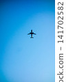 A passenger plane flying through a clear blue sky. 141702582