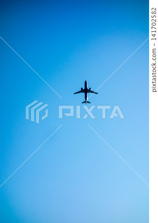A passenger plane flying through a clear blue sky. A passenger plane flying through a clear blue sky. 141702582