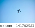 A passenger plane flying through a clear blue sky. 141702583
