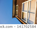 A brick building with large windows bathed in the setting sun under a clear blue sky - a house in the suburbs of London, England. 141702584