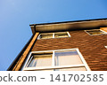A brick building with large windows bathed in the setting sun under a clear blue sky - a house in the suburbs of London, England. 141702585