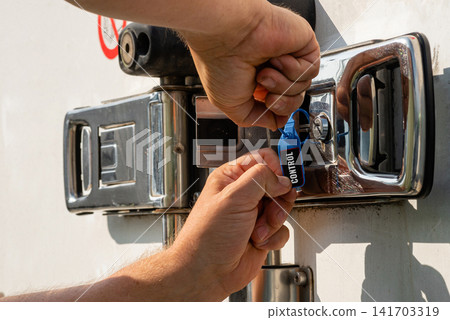 Man locking a delivery truck container door with a blue security tag Man locking a delivery truck container door with a blue security tag 141703319