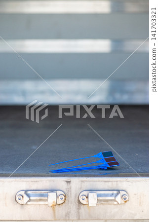 Blue plastic security tag lying on a metal step of a truck Blue plastic security tag lying on a metal step of a truck 141703321
