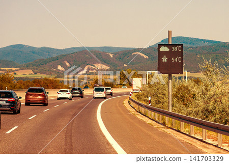 Asphalt highway road stretching towards distant mountain hills at sunset Asphalt highway road stretching towards distant mountain hills at sunset 141703329