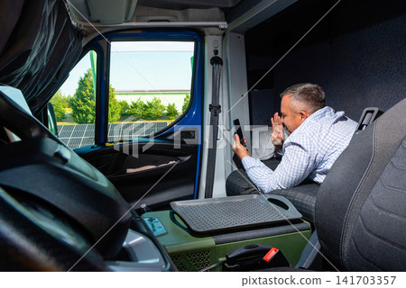 Van driver using his smartphone while sitting inside the vehicle cabin Van driver using his smartphone while sitting inside the vehicle cabin 141703357