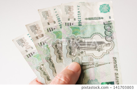 Hand holding several one thousand Russian Ruble banknotes fanned out on a white background. Hand holding several one thousand Russian Ruble banknotes fanned out on a white background. 141703803