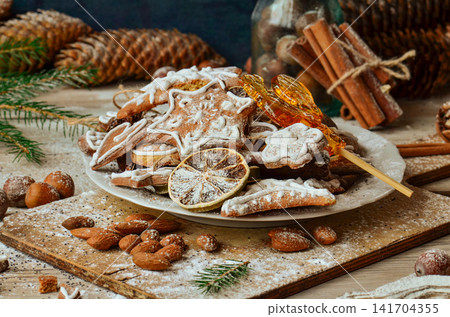 Gingerbread on Christmas table with fir branches and winter spices. Bright sprinkles enhance cheerful holiday theme. 141704355