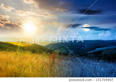 countryside mountain landscape in summer. day meet night. sun and moon over lush grassy pasture on a hill near forest. rural outdoor adventure background. alpine highland of ukraine countryside mountain landscape in summer. day meet night. sun and moon over lush grassy pasture on a hill near forest. rural outdoor adventure background. alpine highland of ukraine 141704997