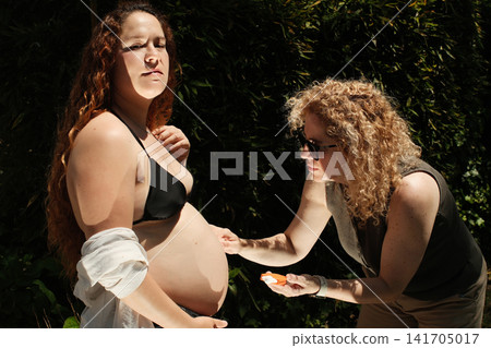 Pregnant woman enjoying a peaceful outdoor maternity lifestyle portrait 141705017
