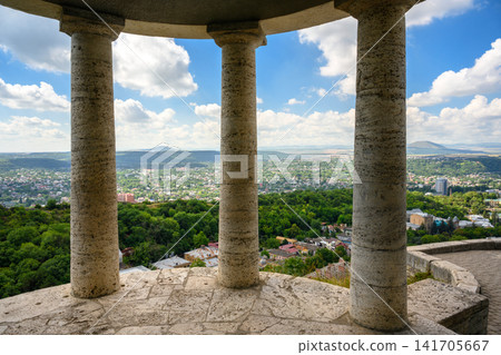View of a city and distant mountains framed by stone columns of a classical rotunda, Pyatigorsk, Russia. Elevated observation deck overlooking a green valley on summer day View of a city and distant mountains framed by stone columns of a classical rotunda, Pyatigorsk, Russia. Elevated observation deck overlooking a green valley on summer day 141705667