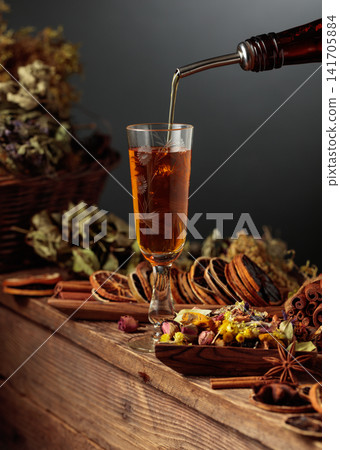 Herbal liquor is poured from a vintage bottle into a glass. Herbal liquor is poured from a vintage bottle into a glass. 141705884