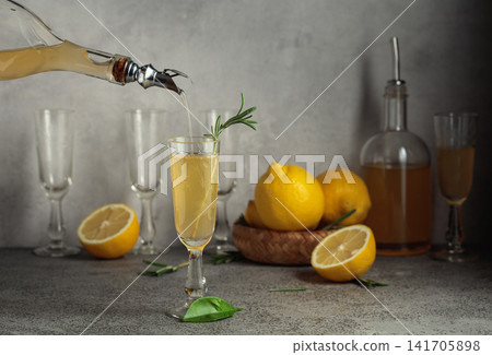 Italian liqueur Limoncello with fresh lemons and rosemary branches on a gray stone table. Italian liqueur Limoncello with fresh lemons and rosemary branches on a gray stone table. 141705898