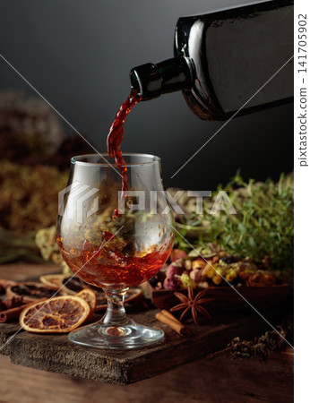 Herbal bitter liqueur is poured from a vintage bottle into a glass. 141705902