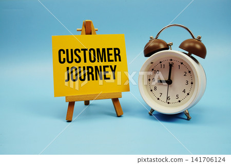 Customer Journey text written on paper card and alarm clock on blue background Customer Journey text written on paper card and alarm clock on blue background 141706124
