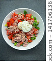 Tuna and tomato salad topped with a poached egg in a bowl 141706136