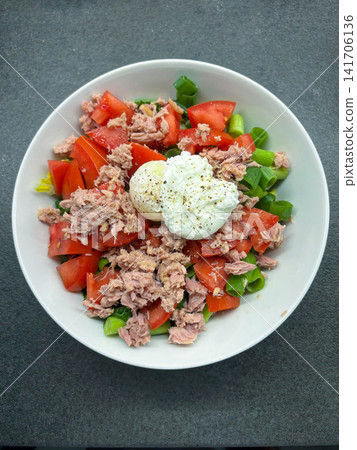 Tuna and tomato salad topped with a poached egg in a bowl 141706136