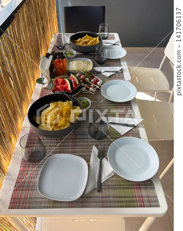 Snack table set on a cozy balcony with chips and appetizers Snack table set on a cozy balcony with chips and appetizers 141706137