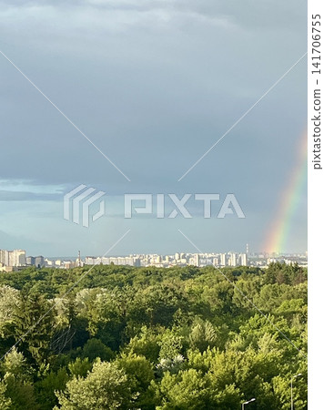 Colorful rainbow over the city skyline and lush green forest after a summer rain. Urban nature landscape with dramatic sky, vibrant colors and scenic horizon. Ideal for concepts of hope, environment, Colorful rainbow over the city skyline and lush green forest after a summer rain. Urban nature landscape with dramatic sky, vibrant colors and scenic horizon. Ideal for concepts of hope, environment, 141706755