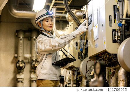 Senior female worker inspecting equipment in boiler room Senior female worker inspecting equipment in boiler room 141706955