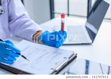 Healthcare professional holding blood sample tube and signing medical document. Healthcare diagnostics and pathology laboratory test results concept. Healthcare professional holding blood sample tube and signing medical document. Healthcare diagnostics and pathology laboratory test results concept. 141707813