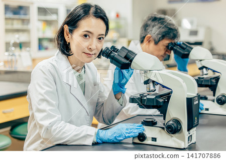 在實驗室中使用顯微鏡進行研究的研究人員 在實驗室中使用顯微鏡進行研究的研究人員 141707886