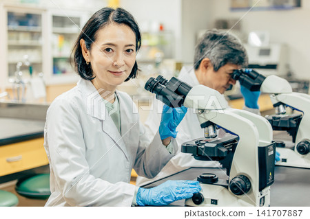 在實驗室中使用顯微鏡進行研究的研究人員 在實驗室中使用顯微鏡進行研究的研究人員 141707887