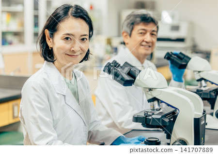 在實驗室中使用顯微鏡進行研究的研究人員 在實驗室中使用顯微鏡進行研究的研究人員 141707889
