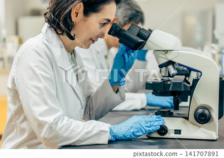 在實驗室中使用顯微鏡進行研究的研究人員 在實驗室中使用顯微鏡進行研究的研究人員 141707891