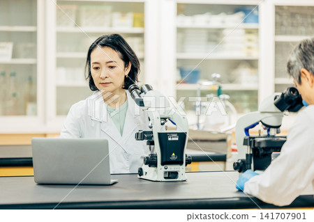 在實驗室中使用顯微鏡進行研究的研究人員 在實驗室中使用顯微鏡進行研究的研究人員 141707901