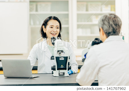 在實驗室中使用顯微鏡進行研究的研究人員 在實驗室中使用顯微鏡進行研究的研究人員 141707902