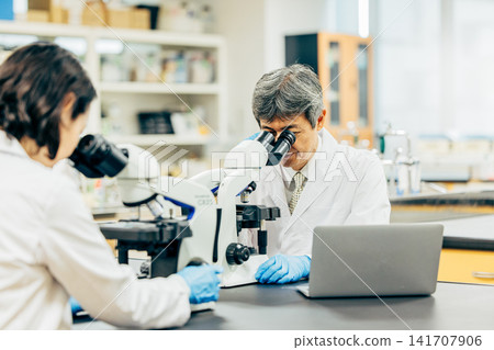 在實驗室中使用顯微鏡進行研究的研究人員 在實驗室中使用顯微鏡進行研究的研究人員 141707906