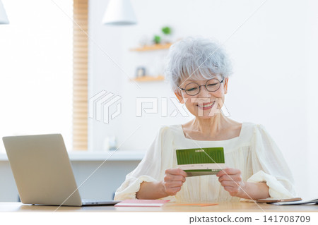 A senior woman looking at her bankbook in the living room A senior woman looking at her bankbook in the living room 141708709
