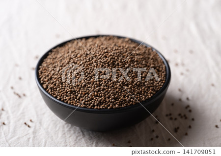 Perilla seeds in a black bowl on white cotton fabric background, Asian healthy ingredients Perilla seeds in a black bowl on white cotton fabric background, Asian healthy ingredients 141709051