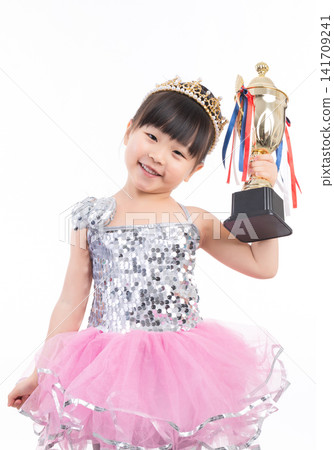 Proud Little Girl in Princess Dress Holding Gold Trophy Cup, Talented Child Celebrating Success and Victory Proud Little Girl in Princess Dress Holding Gold Trophy Cup, Talented Child Celebrating Success and Victory 141709241