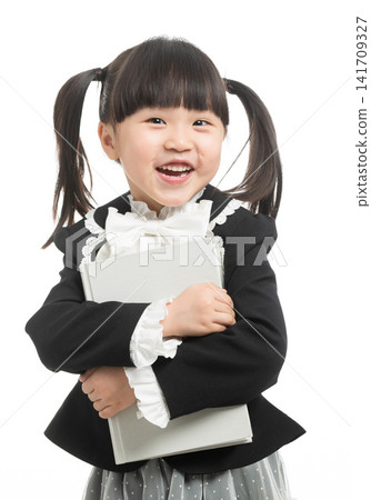 Happy Asian schoolgirl hugging a textbook and laughing, academic achievement and love for school. Happy Asian schoolgirl hugging a textbook and laughing, academic achievement and love for school. 141709327