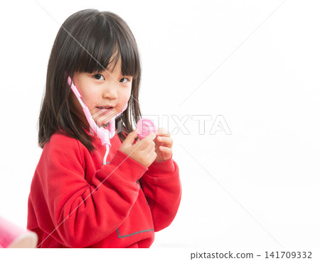 Little girl wearing a red sweater playing with a pink toy stethoscope, dreaming of being a doctor. Little girl wearing a red sweater playing with a pink toy stethoscope, dreaming of being a doctor. 141709332