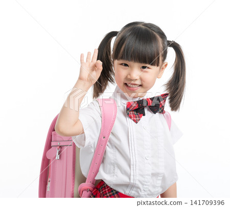 Cheerful little girl in school uniform making OK sign with hand, successful education concept. Cheerful little girl in school uniform making OK sign with hand, successful education concept. 141709396
