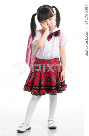 Unhappy and tired Asian schoolgirl with backpack standing against white background, school stress. 141709397