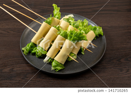 raw Tofu Skin Rolls Stuffed With Crisp Green Lettuce Skewered For Cooking raw Tofu Skin Rolls Stuffed With Crisp Green Lettuce Skewered For Cooking 141710265