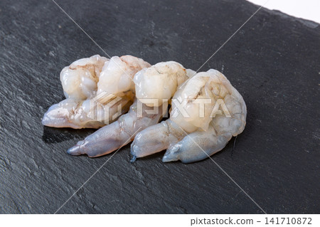 raw shucked peeled shrimp meat showing natural juicy texture 141710872