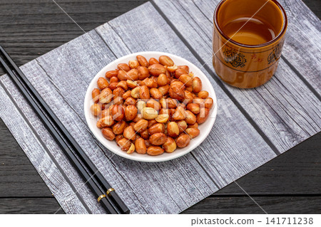 fried yellow peanuts served in small ceramic bowl 141711238