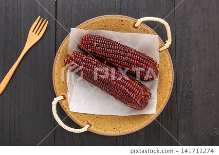 boiled black sticky corn on cobs served on a plate isolated on white background boiled black sticky corn on cobs served on a plate isolated on white background 141711274
