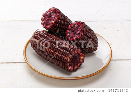 boiled black sticky corn on cobs served on a plate isolated on white background boiled black sticky corn on cobs served on a plate isolated on white background 141711342
