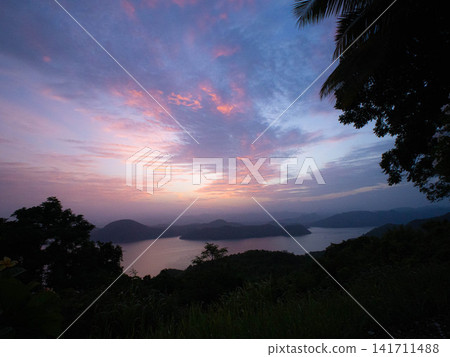 Scenic landscape of calm lake and mountains under colorful sky at dawn Scenic landscape of calm lake and mountains under colorful sky at dawn 141711488