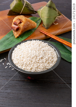 raw white glutinous sticky rice with wrapped bamboo rice dumplings raw white glutinous sticky rice with wrapped bamboo rice dumplings 141711619