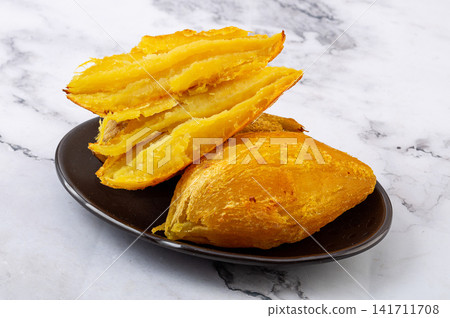 roasted yellow sweet potato pieces served in dark bowl 141711708