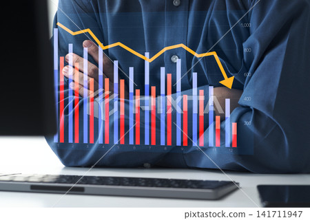 Declining sales and poor performance. Falling profits and financial challenges. Arms crossed, staring at the graphs displayed on the computer. Declining sales and poor performance. Falling profits and financial challenges. Arms crossed, staring at the graphs displayed on the computer. 141711947