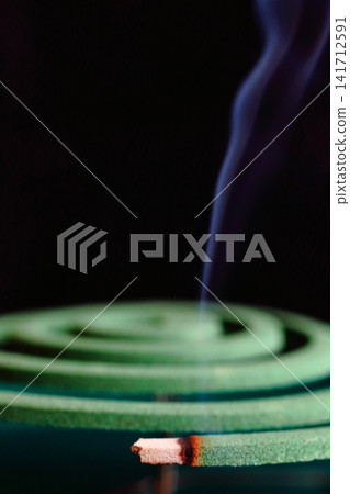 A vertical composition of a mosquito coil with smoke rising from it. A vertical composition of a mosquito coil with smoke rising from it. 141712591