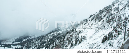 Snow blankets mountains under dense fog providing a serene view Snow blankets mountains under dense fog providing a serene view 141713311