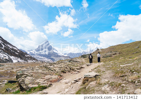Scenic Hiking Trail with Iconic Matterhorn Mountain in Zermatt, Switzerland, Beautiful Swiss Alps Landscape under Blue Sky and White Clouds, Famous Landmark and popular European Travel Destination Scenic Hiking Trail with Iconic Matterhorn Mountain in Zermatt, Switzerland, Beautiful Swiss Alps Landscape under Blue Sky and White Clouds, Famous Landmark and popular European Travel Destination 141713412